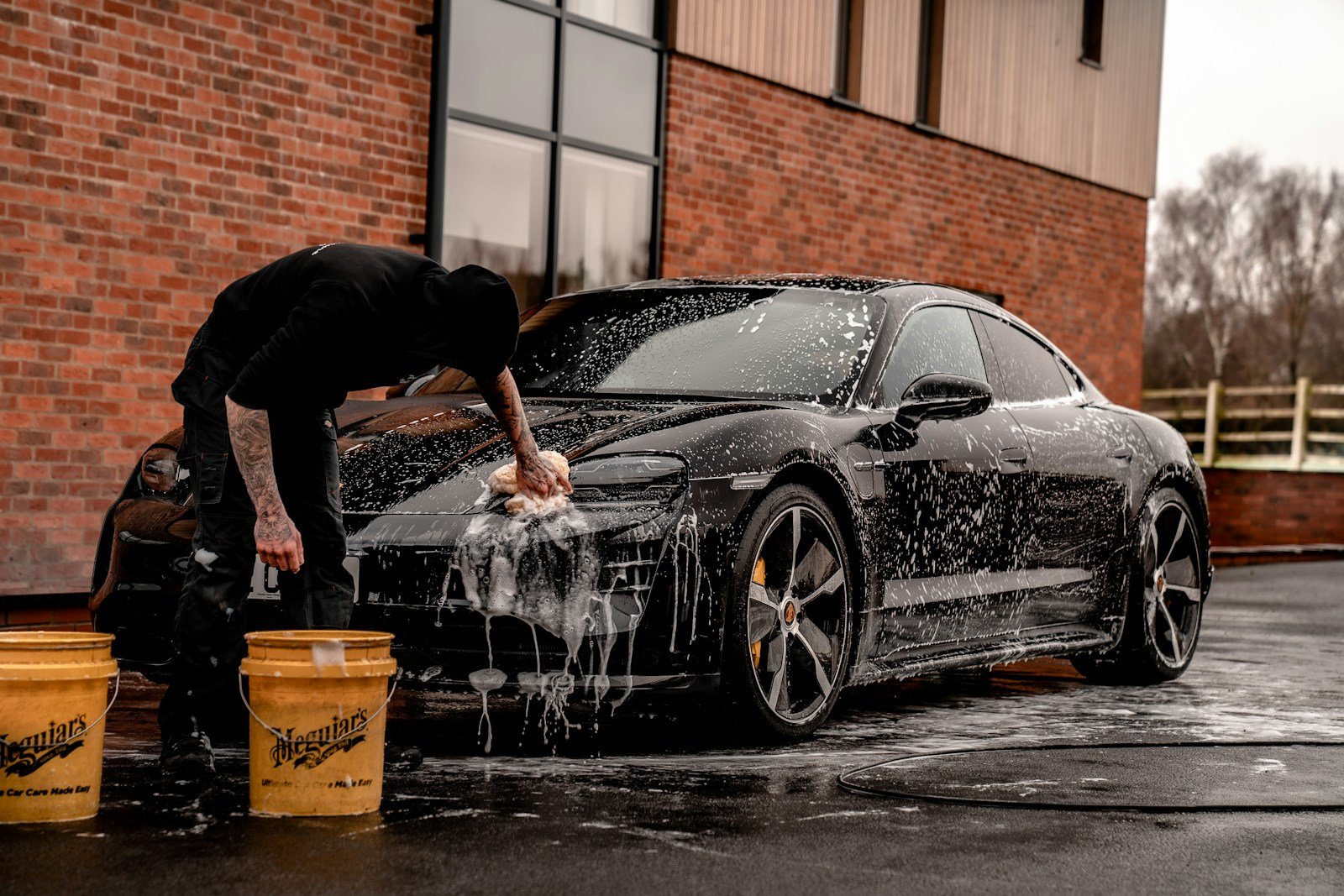 Photo by Brad Starkey man in black t-shirt and black pants doing water splash on black coupe during daytime